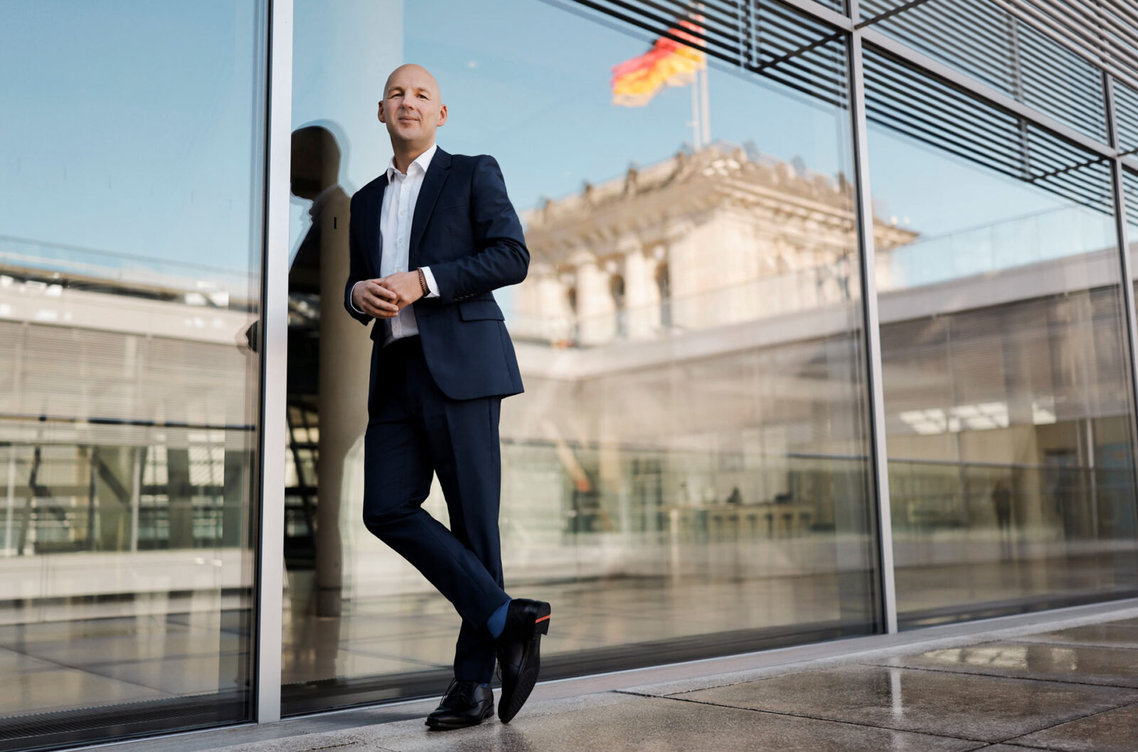 Ganzkörper Portrait von Marc Biadacz vor Glasfront eines Gebäudes